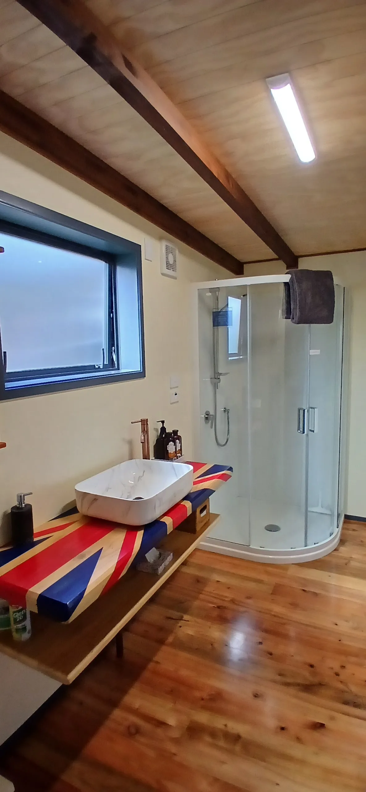 The bathroom with a stone vessel sink and corner glass shower