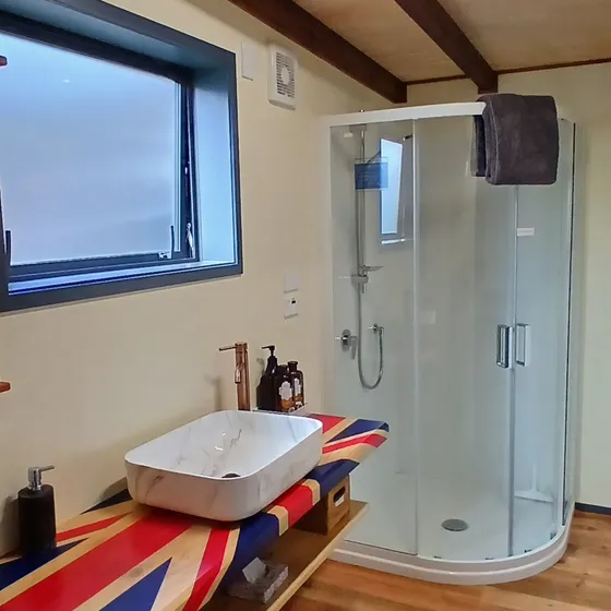The bathroom with a stone vessel sink and corner glass shower