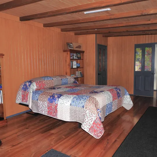 A warm bedroom with patchwork quilt and a door open to the outside