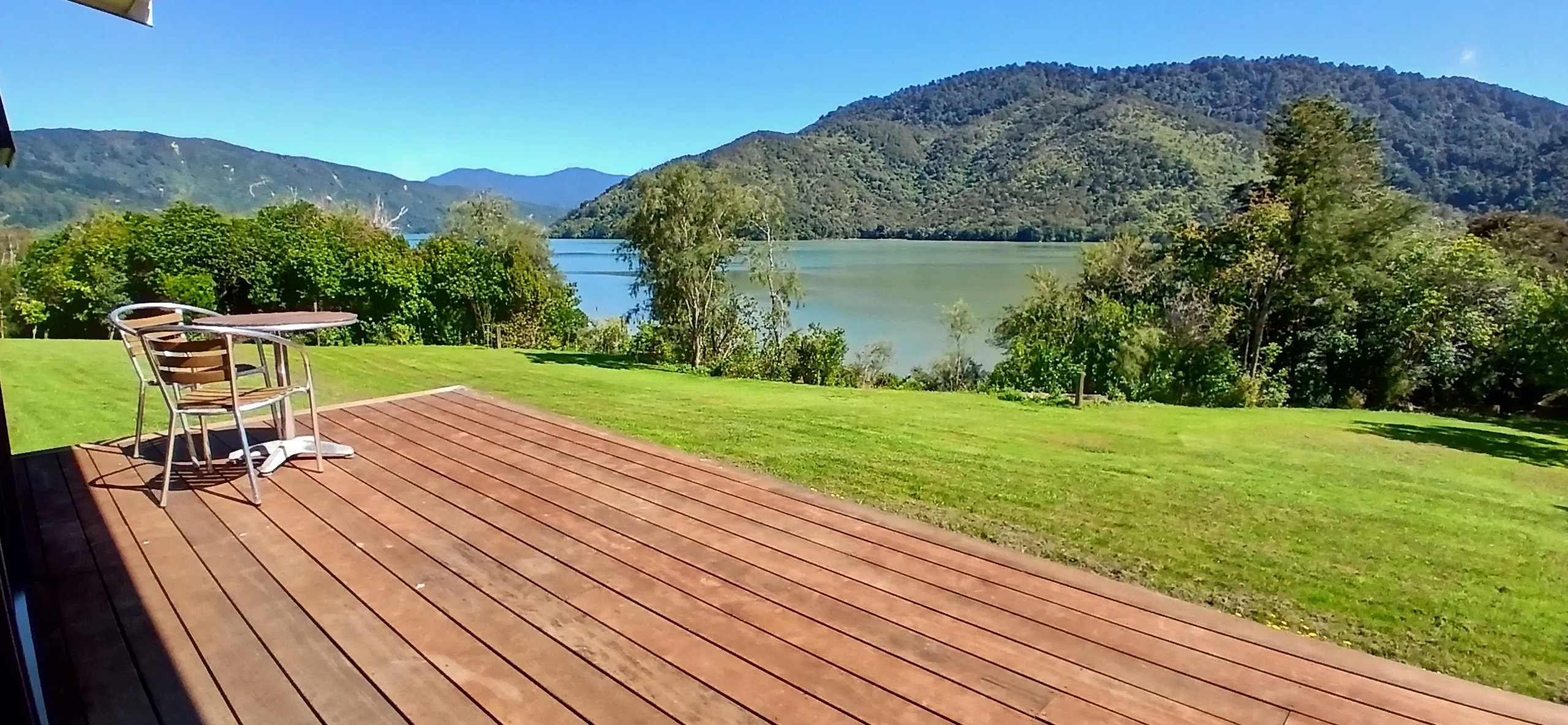A cafe table on the deck overlooking the calm green water of the Sounds