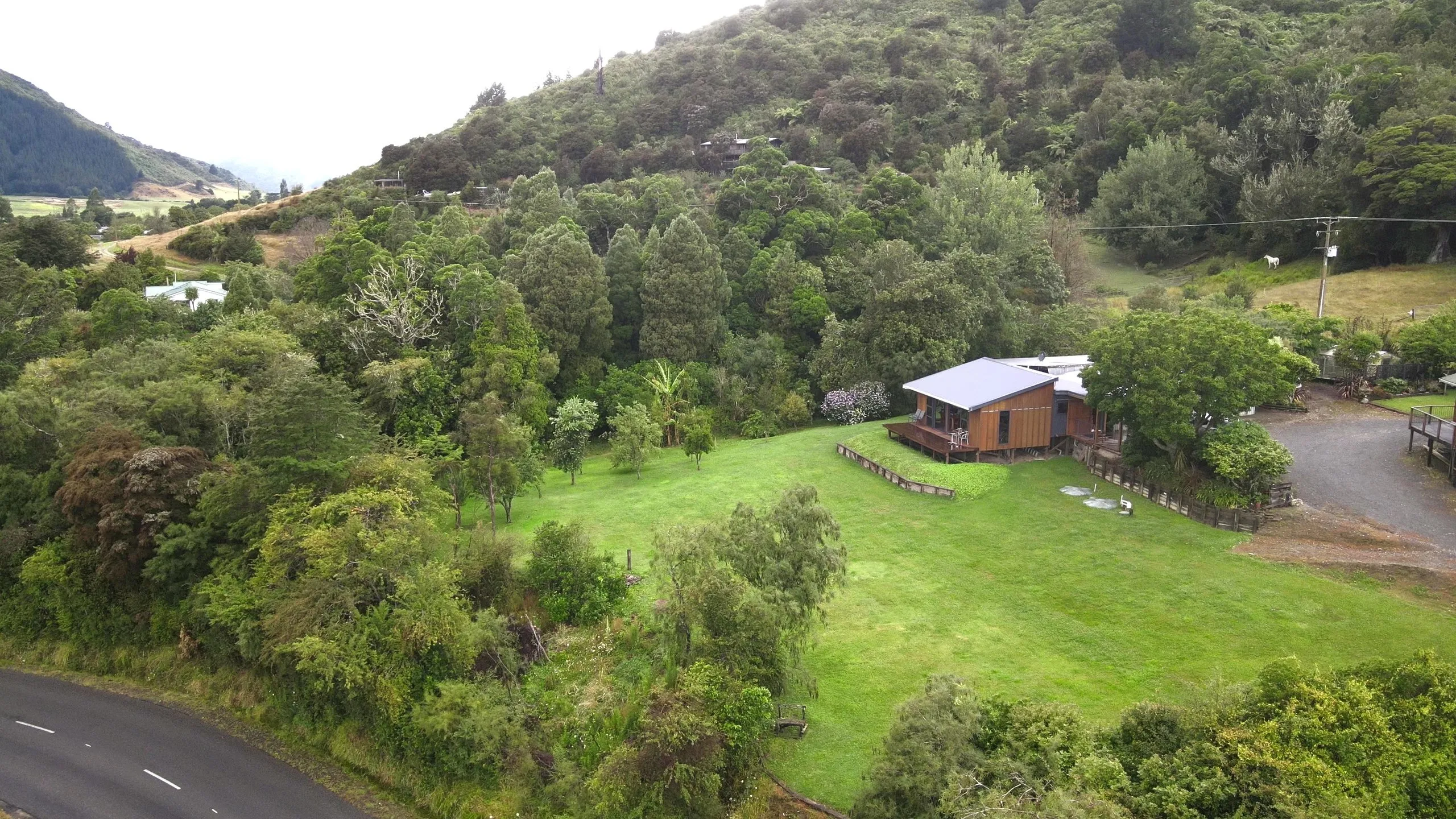 The hand-built timber cabin and its deck, with chairs set out against the native bush hillside