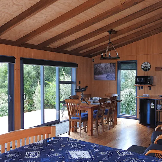 The open-plan living room with lounge chairs and full-height glass framing the water