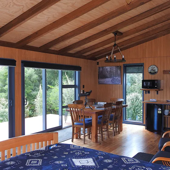 The open-plan living room with lounge chairs and full-height glass framing the water